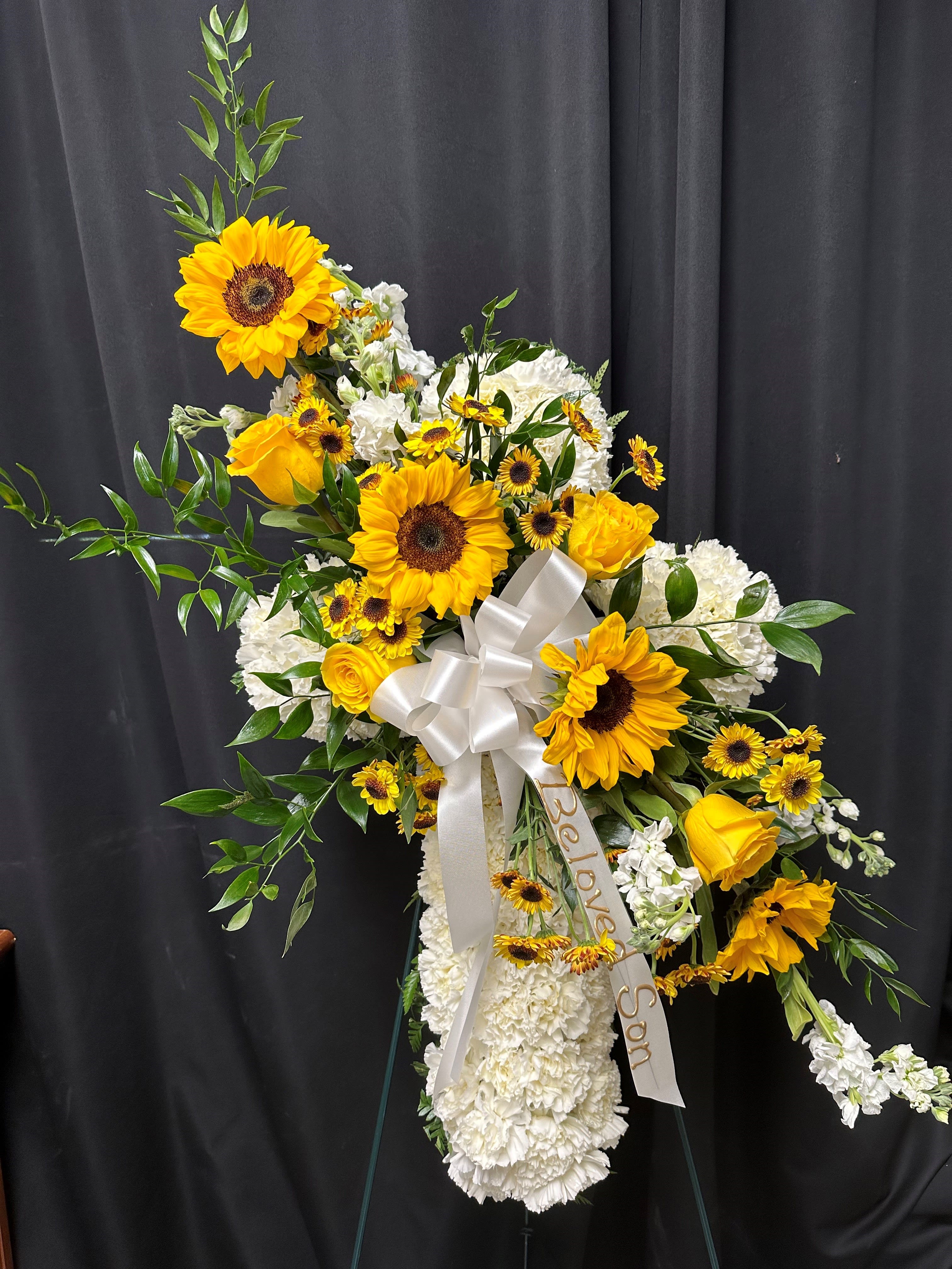 Standing floral spray with sunflowers, white blooms, and a white ribbon