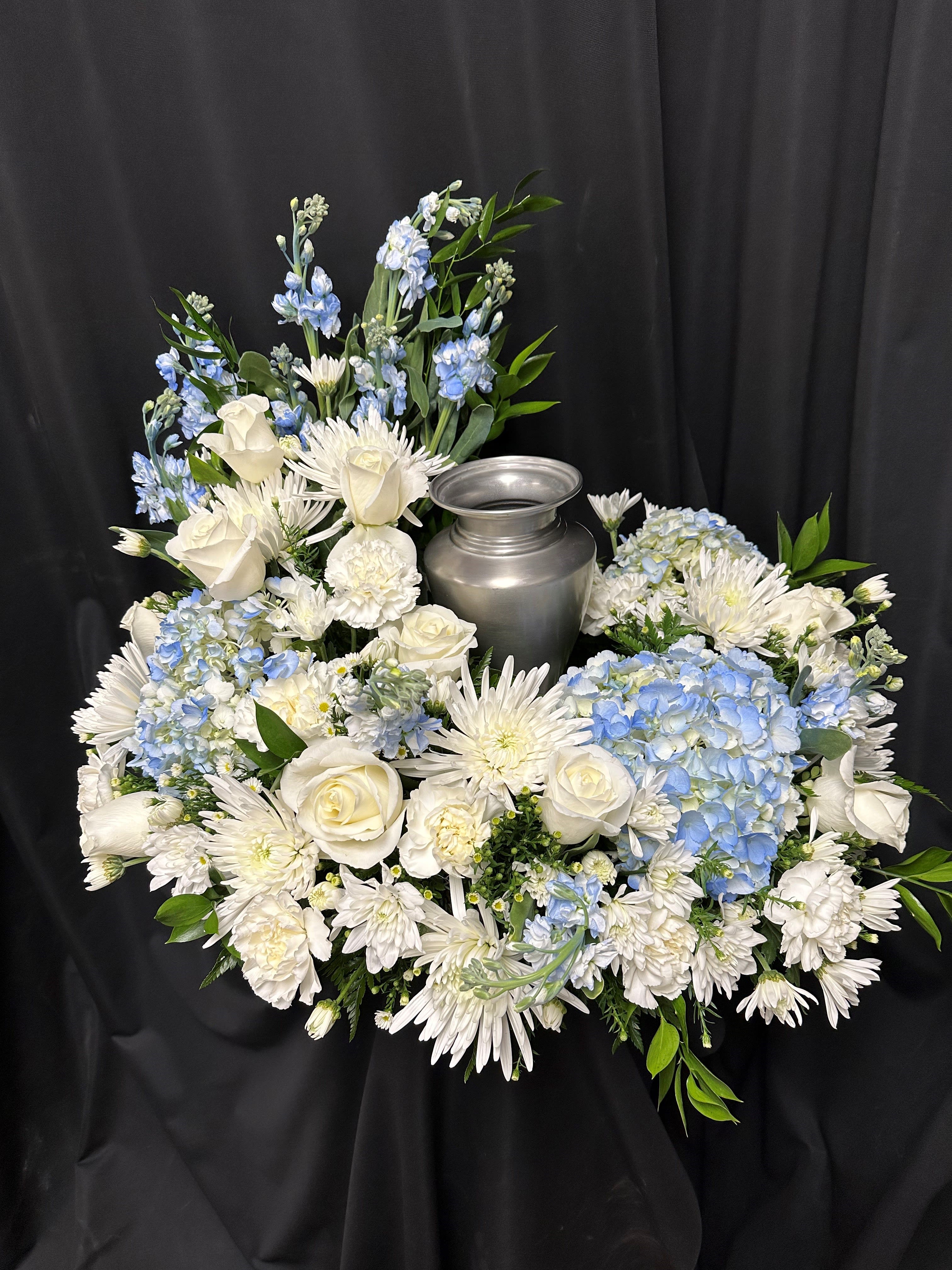 White and blue floral arrangement around a silver urn
