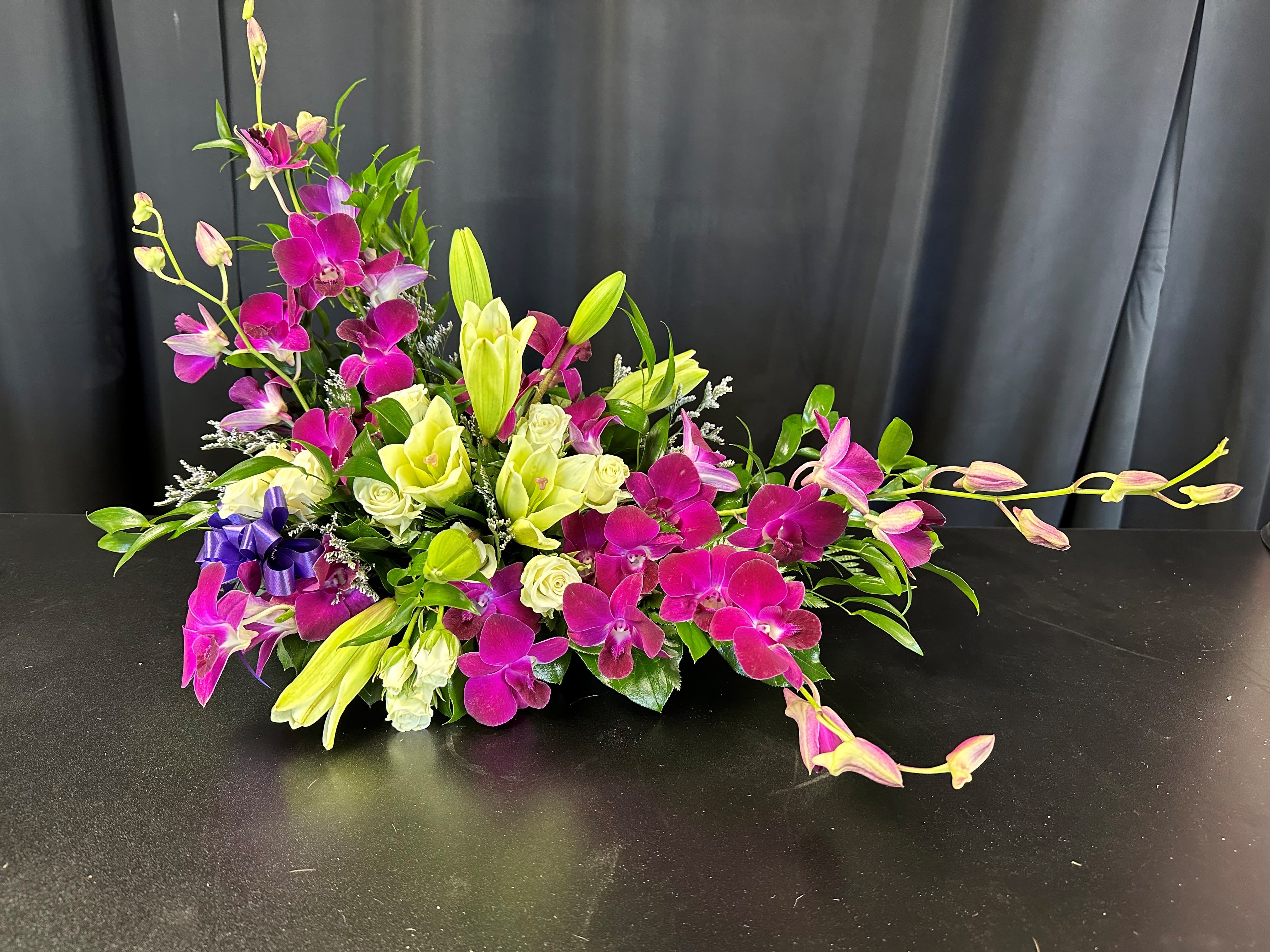 Magenta orchids and pale lilies arranged low on a black surface