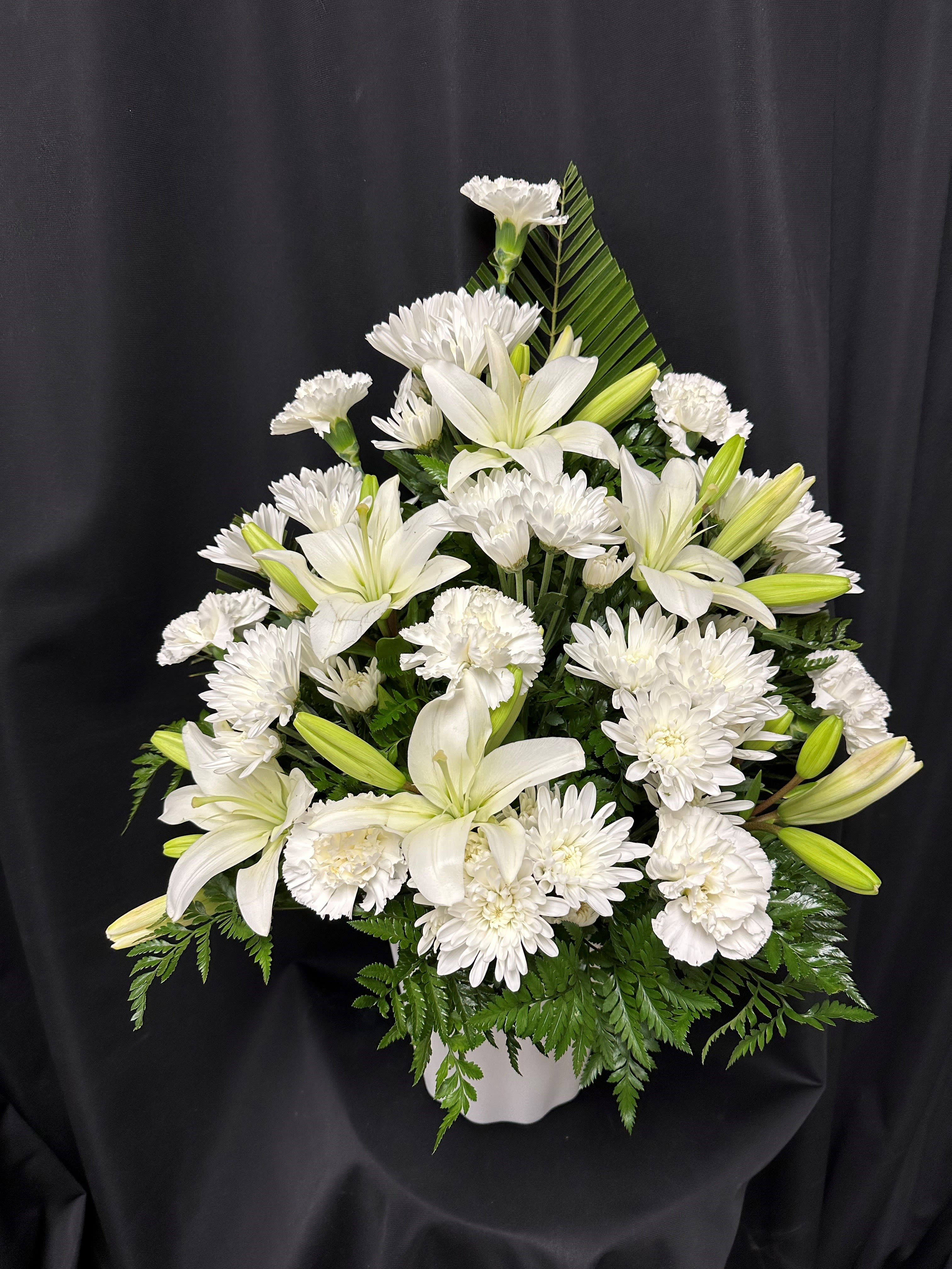 White lilies and chrysanthemums arranged in a white vase