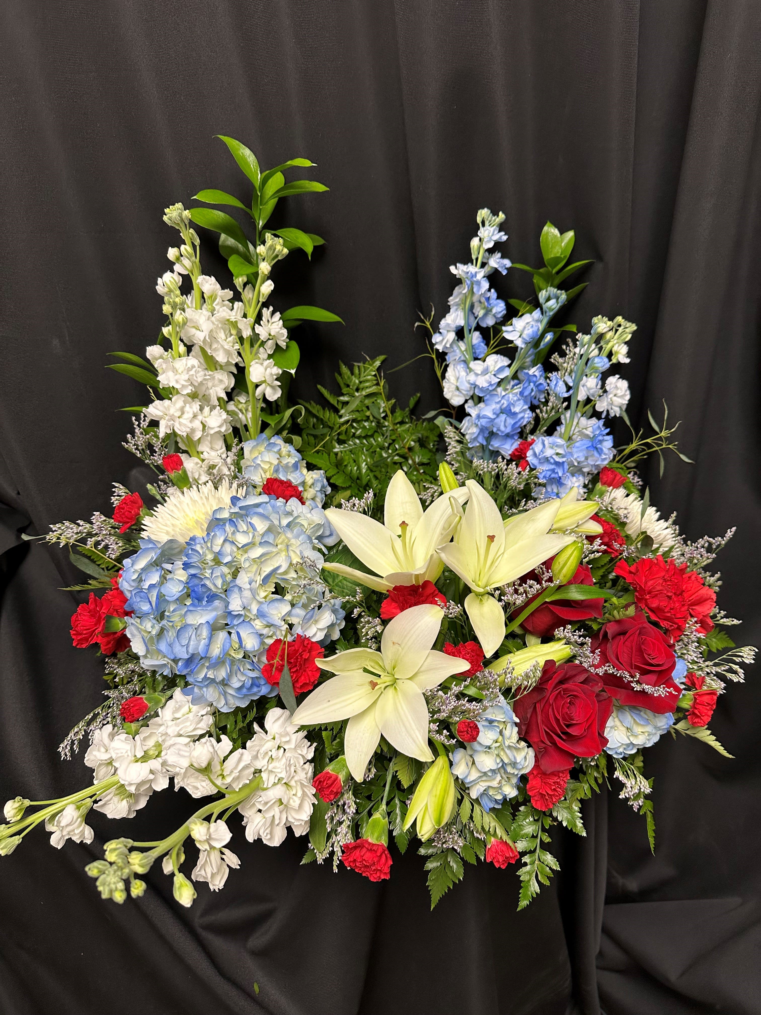 Mixed bouquet with white lilies, blue hydrangeas, red roses, and white stock