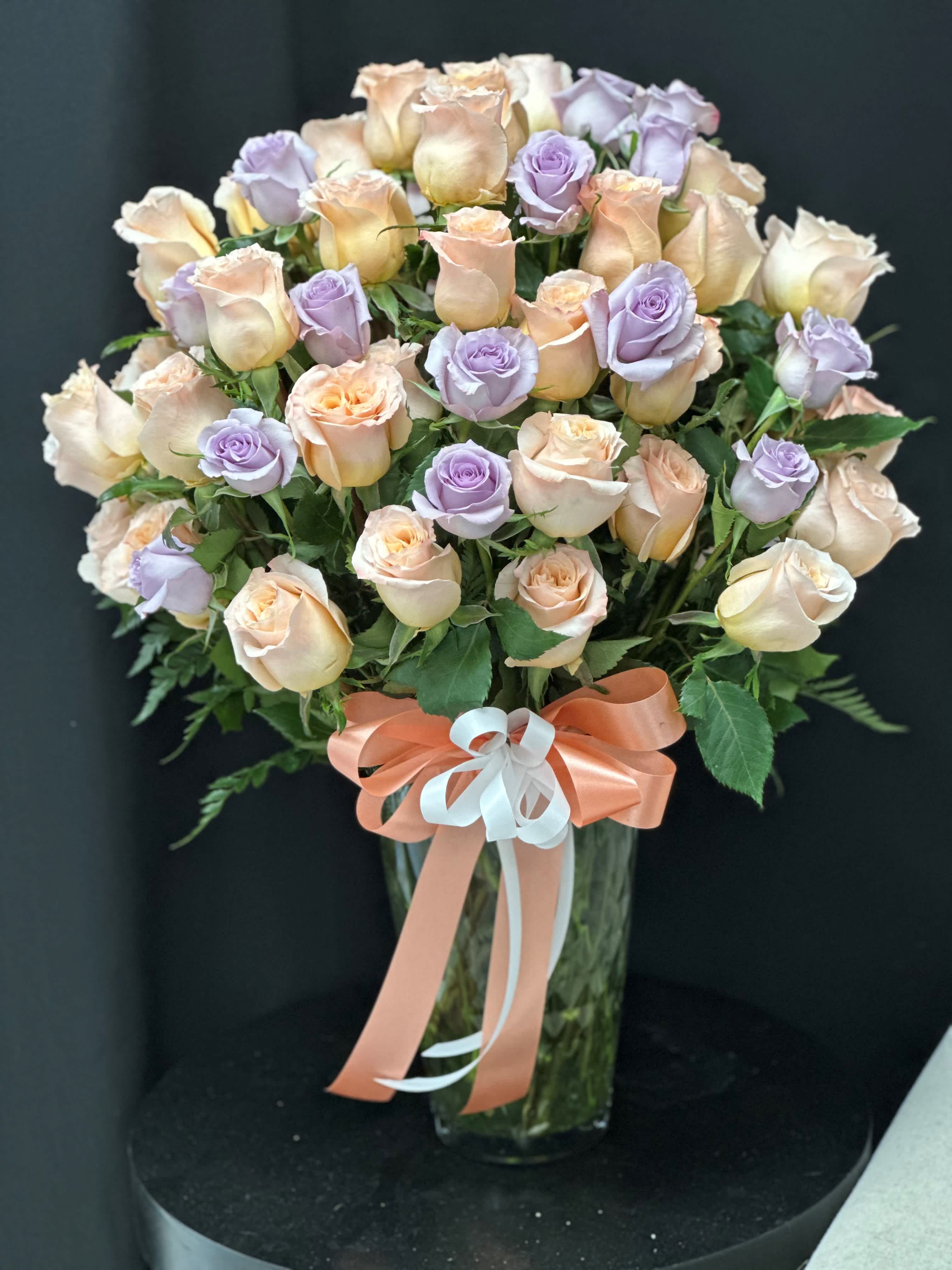 Applause Luxury Rose Bouquet - Celebrate the shining star in your life, whose love knows no bounds, with our exquisite bouquet of pink and lavender premium long-stemmed roses. Each bloom, with its abundance of swirling petals, is a symbol of your endless gratitude and admiration. Expertly arranged in a clear glass vase, this stunning bouquet is a heartfelt tribute to their unwavering presence and boundless love.    