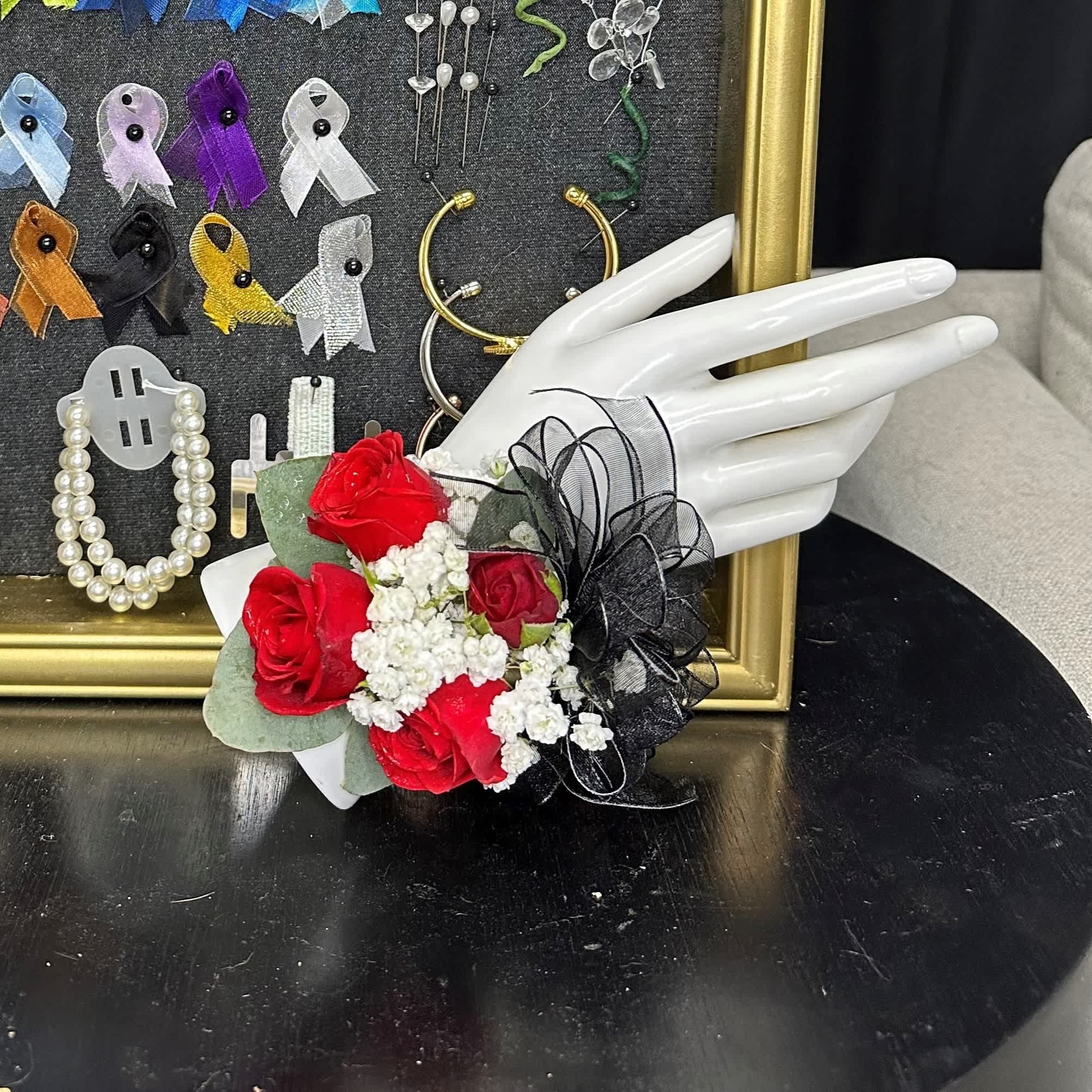 Red roses with white filler flowers and black ribbon on a mannequin hand
