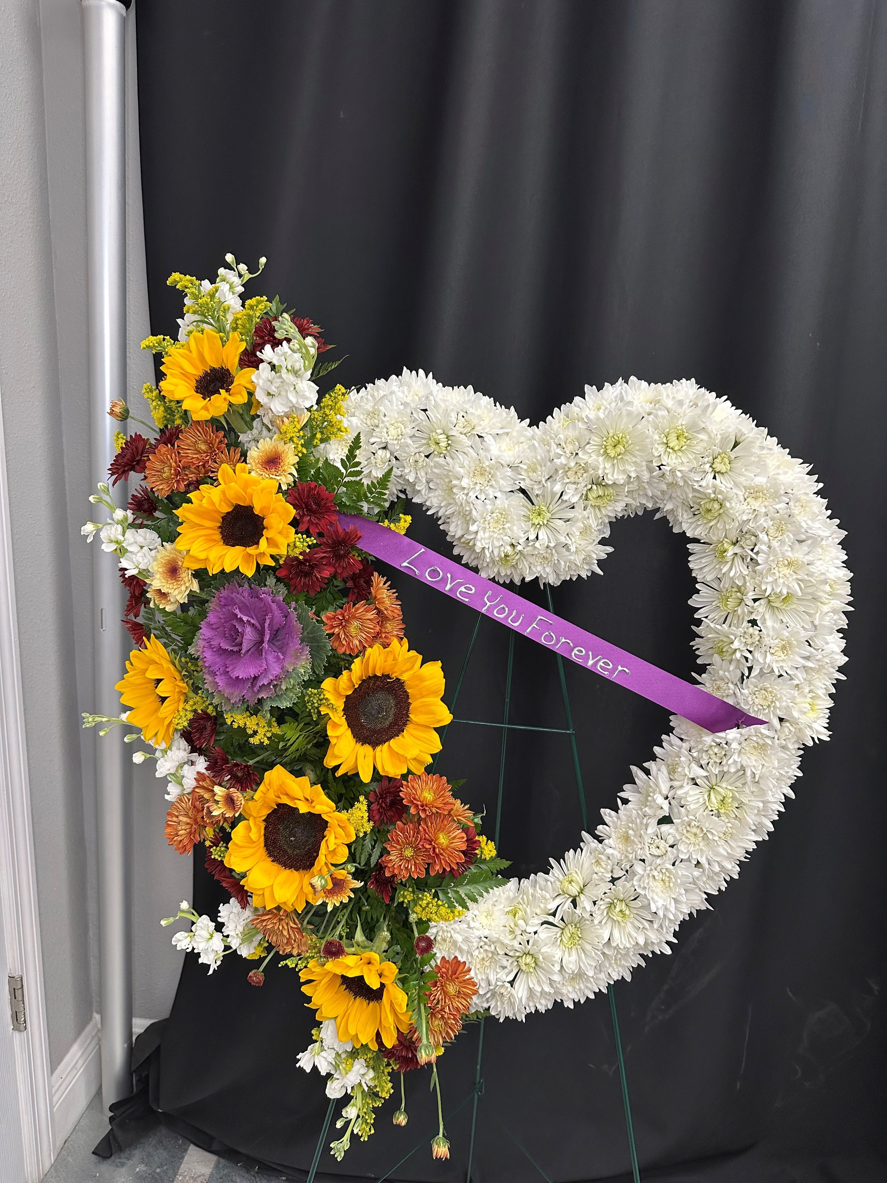 Heart-shaped floral tribute with sunflowers and white chrysanthemums