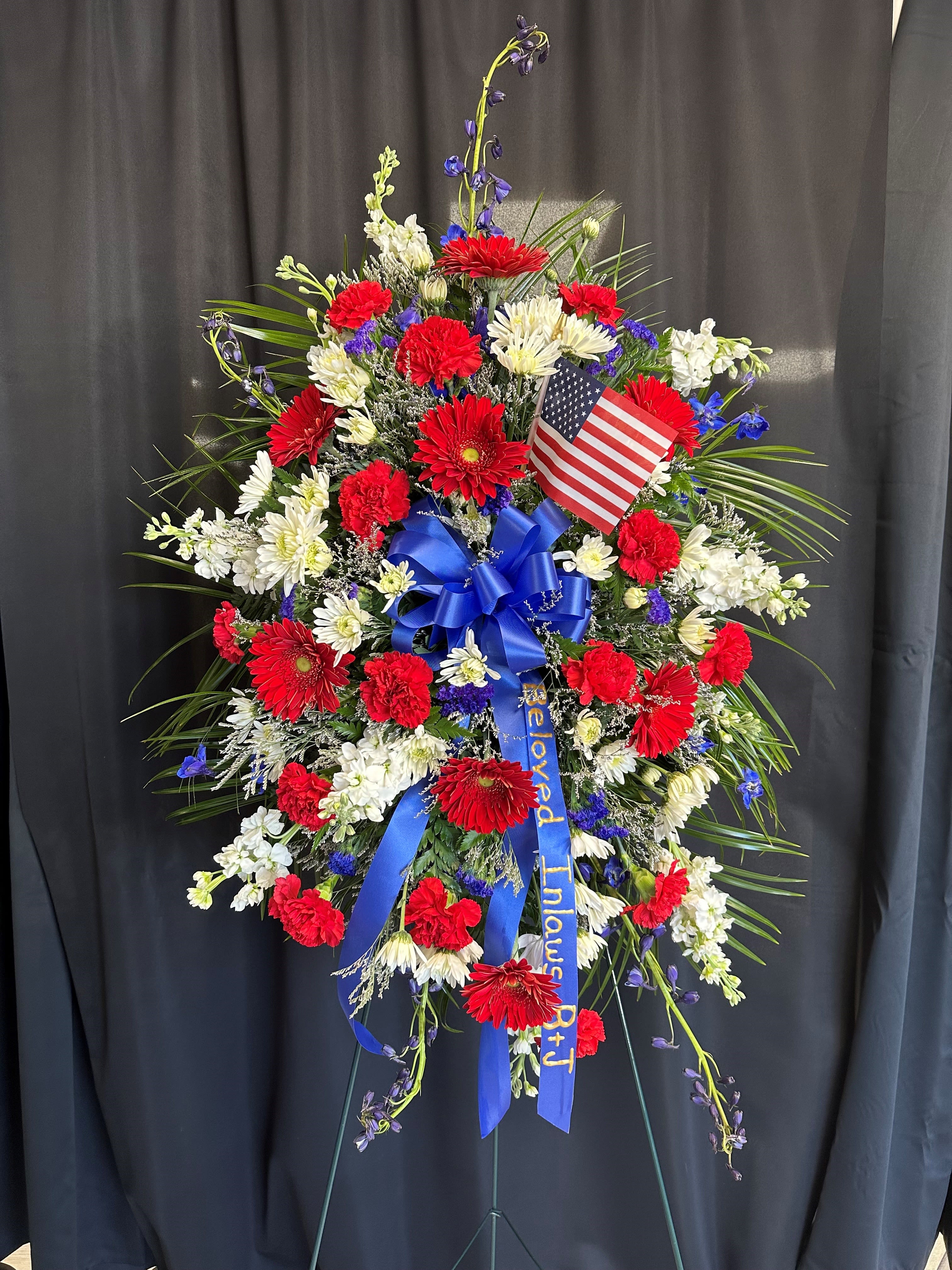 Standing patriotic floral spray with red, white, and blue flowers and an American flag