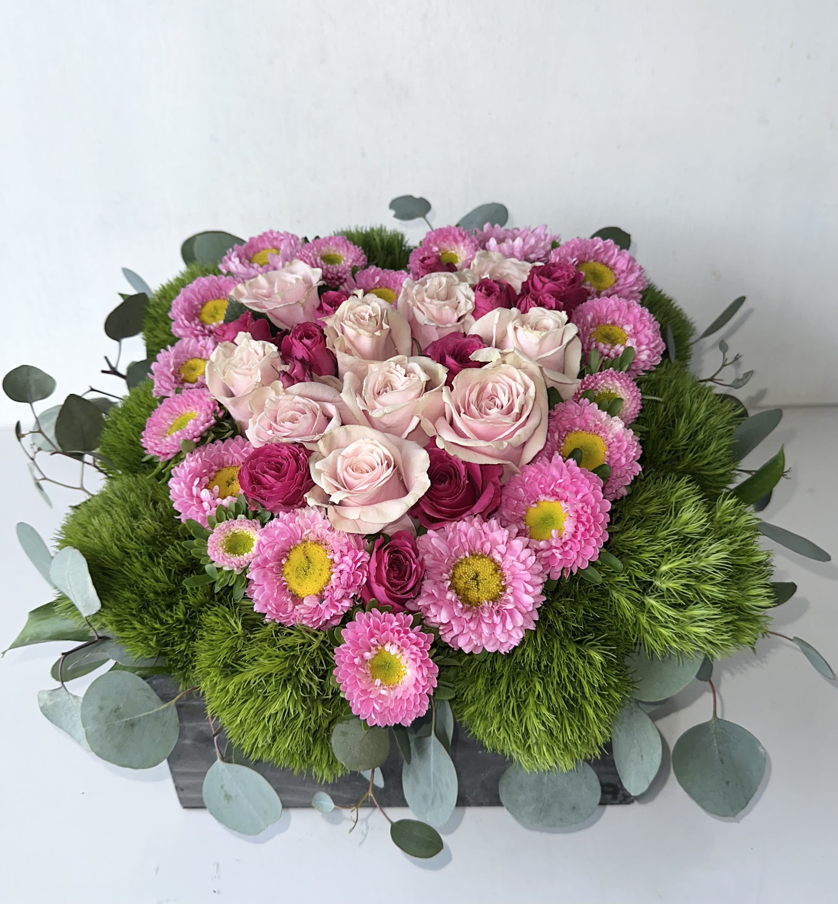 Pink roses and daisies arranged in a low rectangular box
