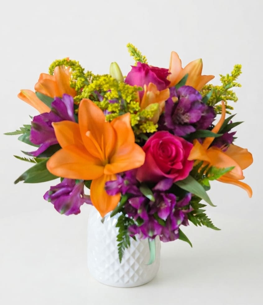 Orange lilies and purple flowers in a white vase with a pink rose