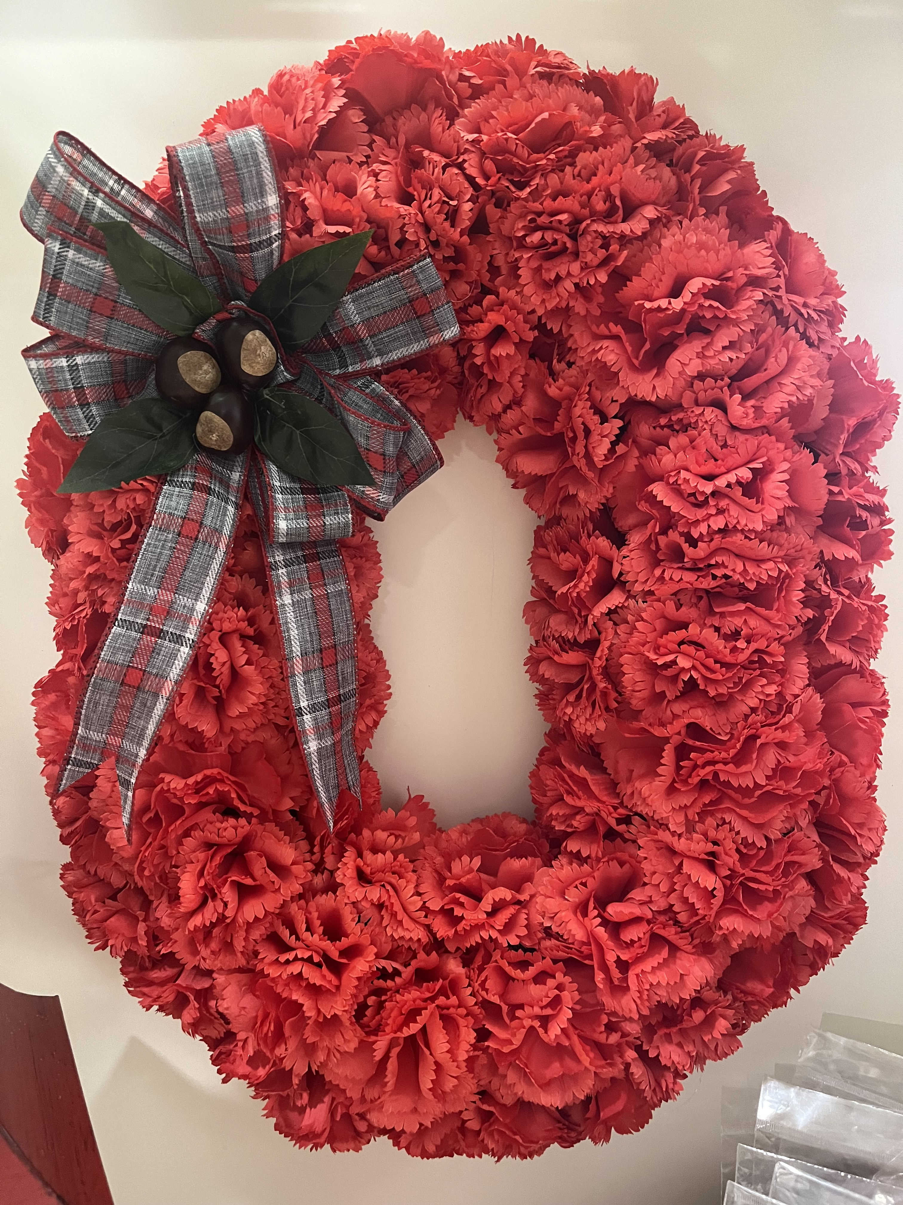 Red carnation wreath with a plaid bow and berry accent
