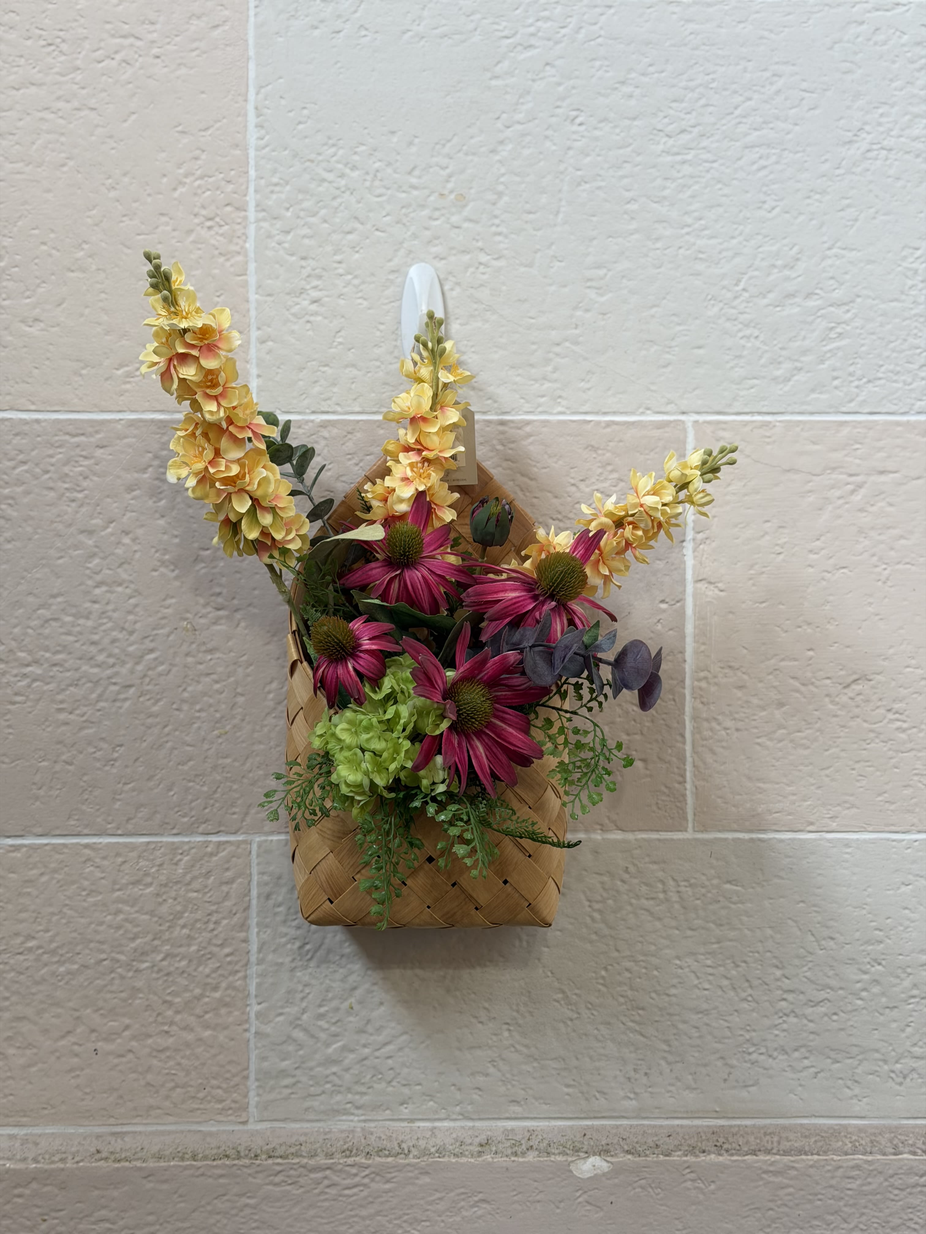 Basket Wall Decor  - A basket wall hanger filled with artificial blooms. 