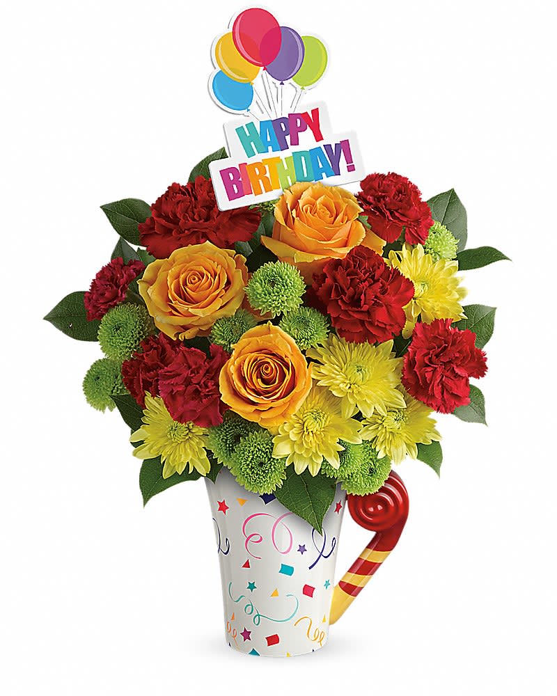 Bright birthday bouquet of red carnations, yellow mums, and orange roses in a confetti mug with a Happy Birthday pick