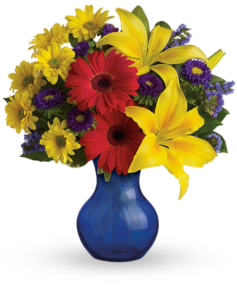 Bright bouquet of yellow lilies, red gerbera daisies and mixed blooms in a blue glass vase