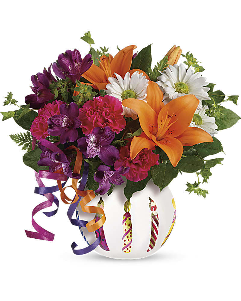 Colorful bouquet of orange lilies, purple alstroemeria, pink carnations, and white daisies in a round candle-print vase