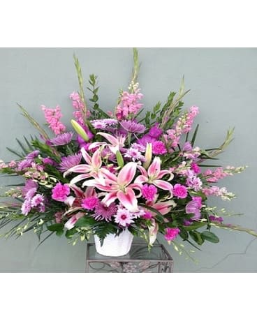 Pink lilies and mixed purple flowers in a white vase