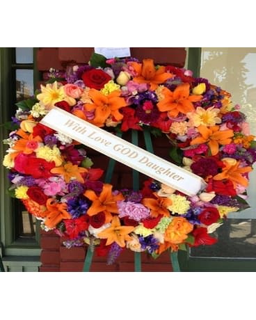 Large colorful funeral wreath with a white memorial ribbon