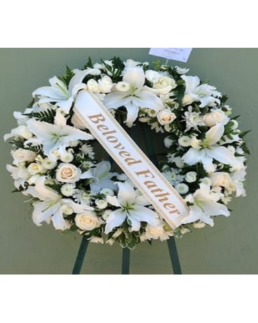 White funeral wreath with lilies and roses on a stand