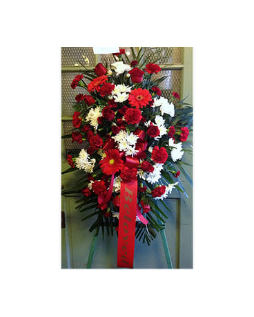 Standing spray of red and white flowers with a red ribbon