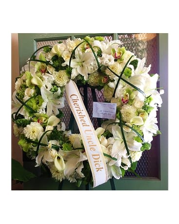 White floral wreath with a condolence ribbon