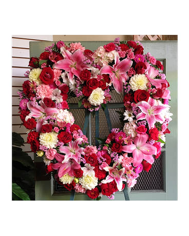 Heart-shaped floral wreath with pink lilies, red roses, and carnations