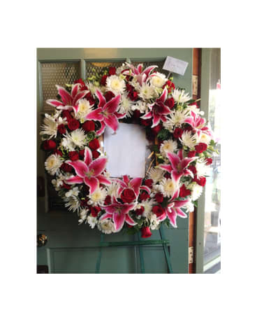 Heart-shaped funeral wreath with pink lilies, red roses, and white flowers