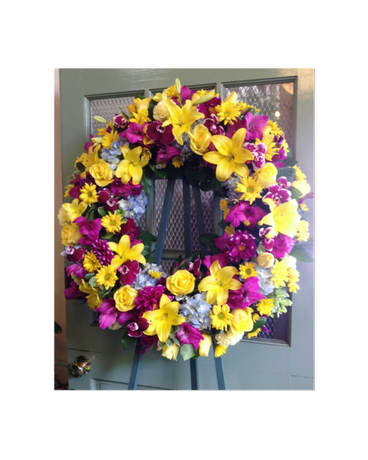 Large yellow and purple floral wreath on a stand