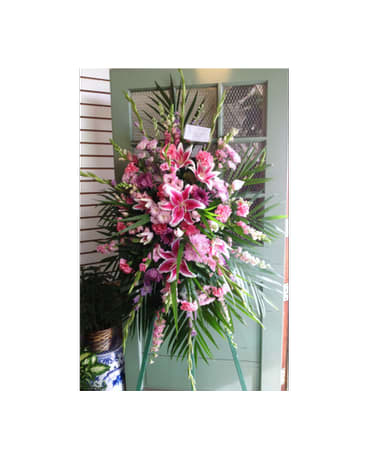 Tall pink and white floral standing spray on a green easel