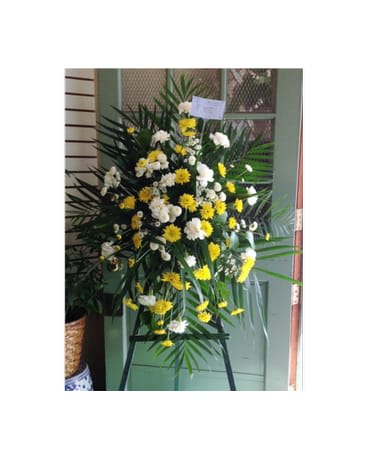 Standing floral spray with yellow and white flowers on an easel