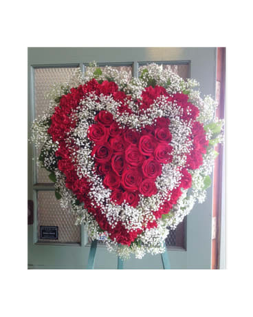 Heart-shaped standing spray of red roses with white baby's breath