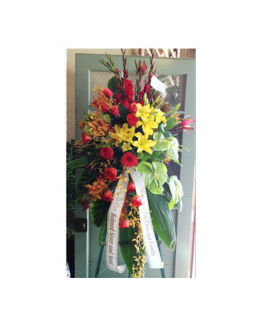 Tall standing floral spray with red, yellow, and orange flowers on an easel