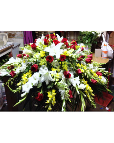 Large floral spray with red roses, white lilies, and yellow flowers