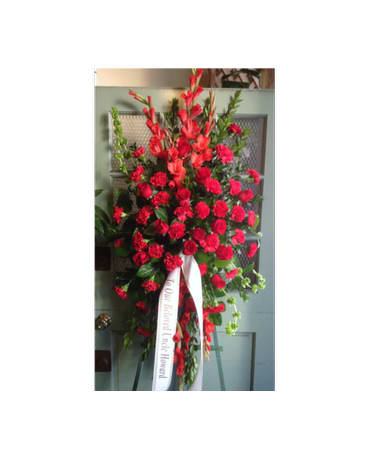 Tall standing spray of red carnations with a white ribbon