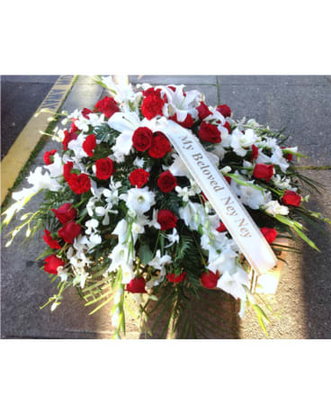 Red and white funeral spray with a memorial ribbon