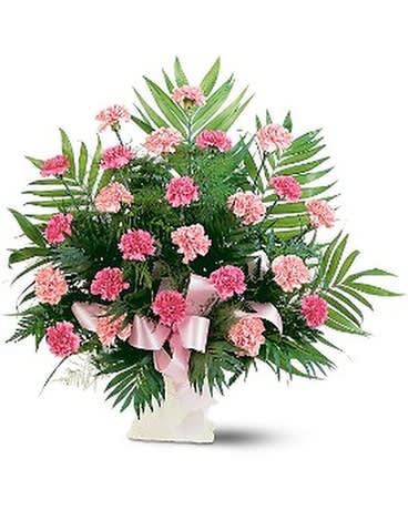 Pink carnations arranged in a white vase with a pink ribbon