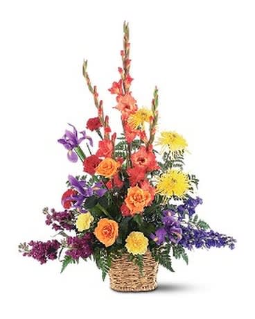 Tall mixed arrangement of orange, yellow, and purple flowers in a woven basket
