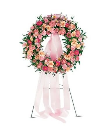 Pink and peach floral wreath on a pink stand with ribbon