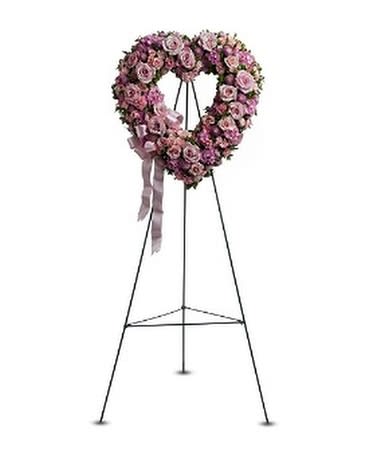 Heart-shaped pink rose funeral wreath on a metal stand