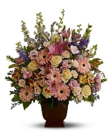 Mixed pink and cream flowers arranged in a brown urn vase