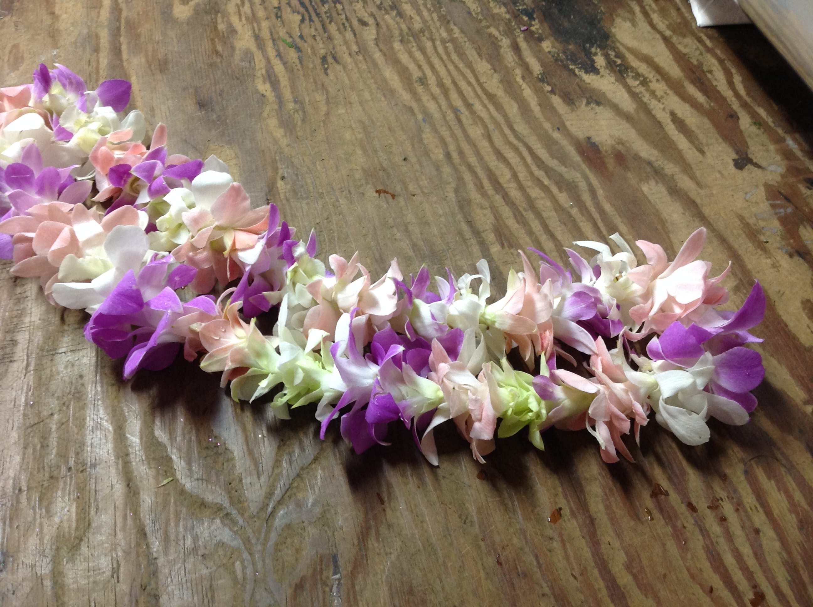 A pastel flower lei made of purple, pink, and white blossoms.