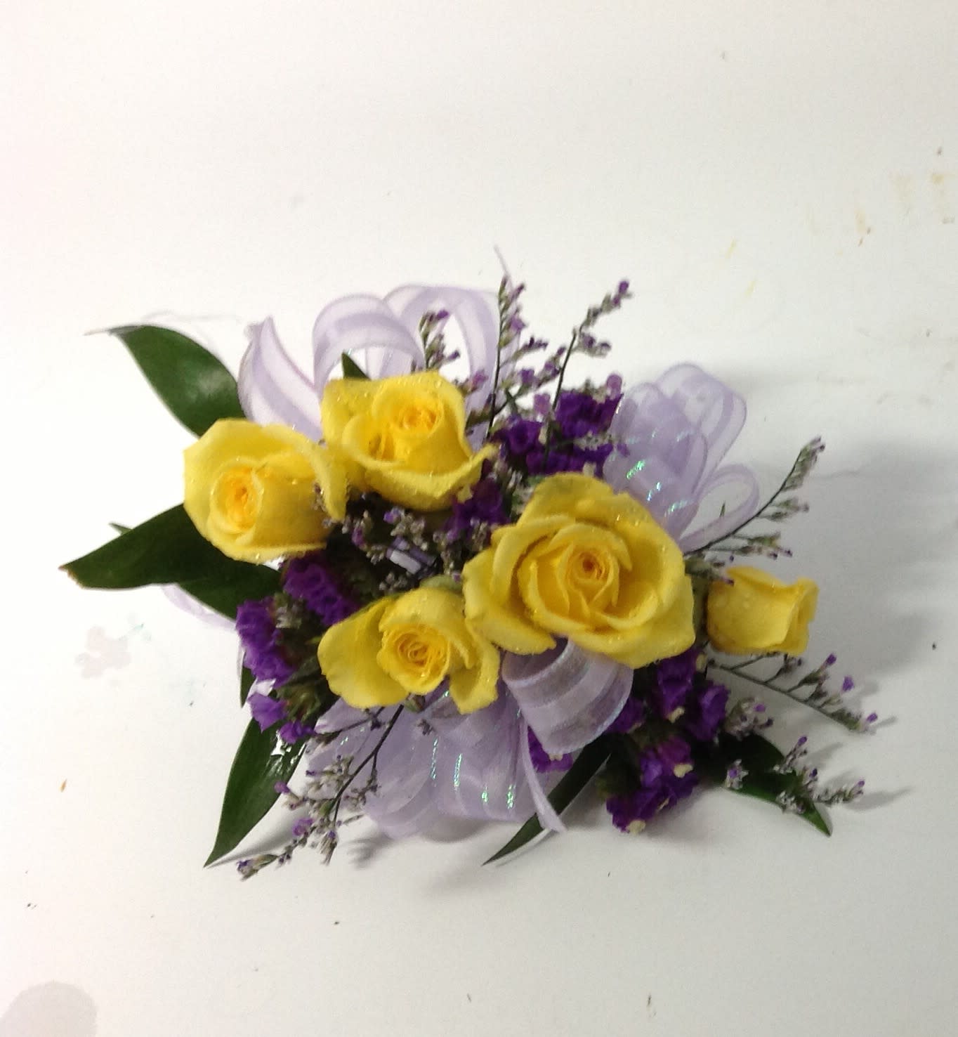 Yellow roses with purple filler and a lavender ribbon bow