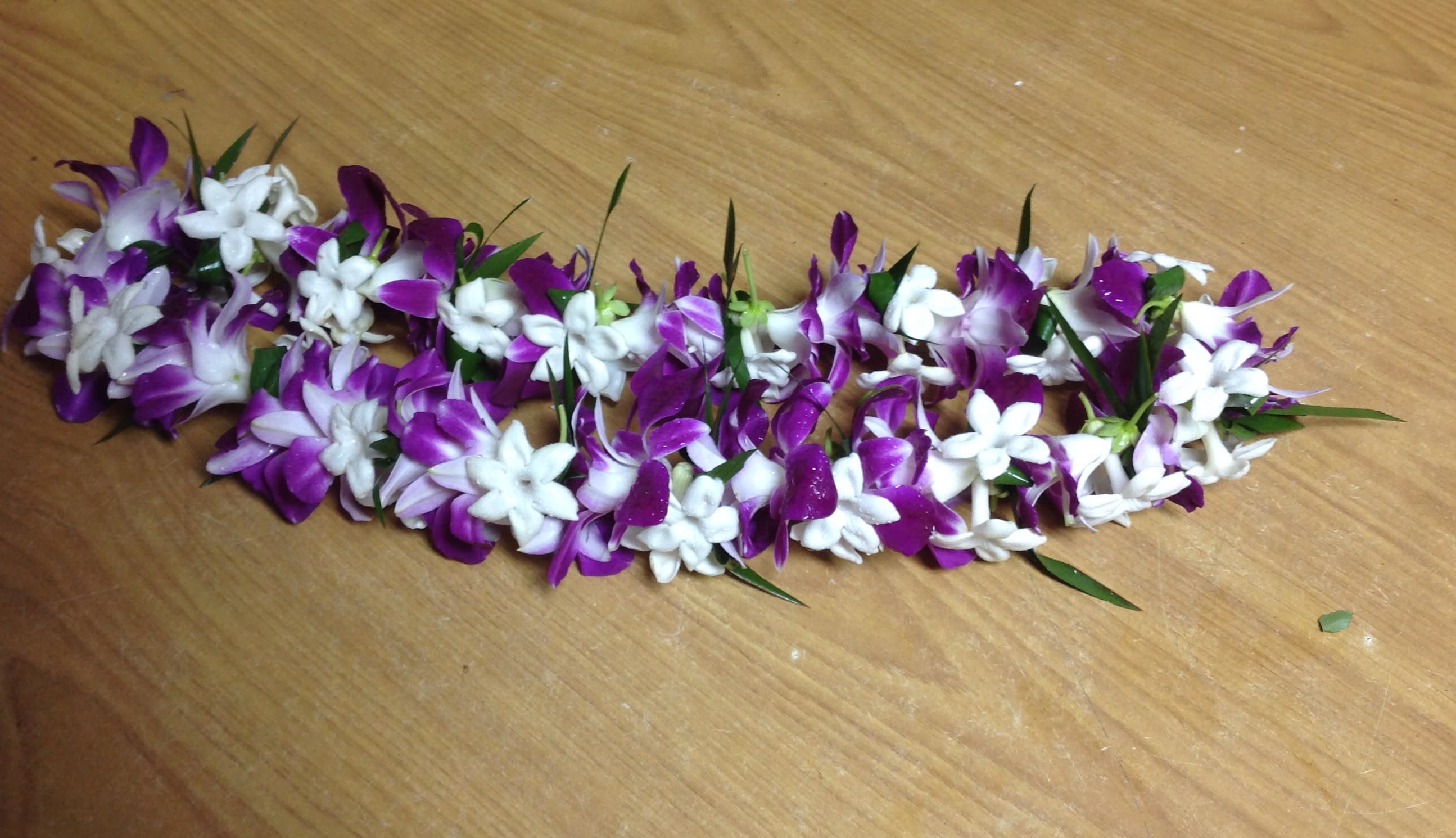 Purple and white flower garland laid on a wooden surface