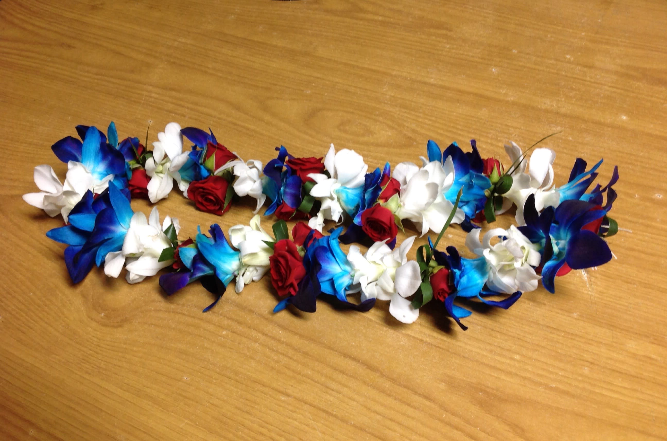 Two floral garlands with blue, white, and red flowers on a wooden surface
