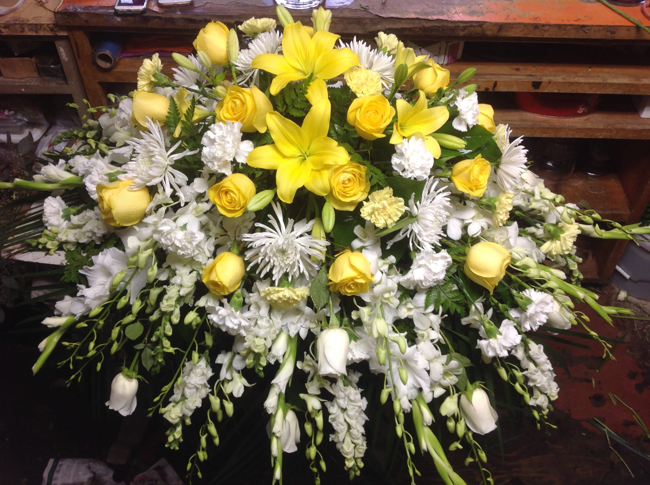 Yellow lilies and roses arranged with white flowers in a large spray