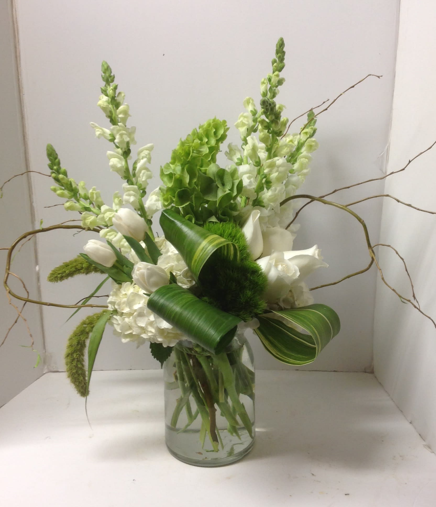 White flowers and green blooms arranged in a glass vase