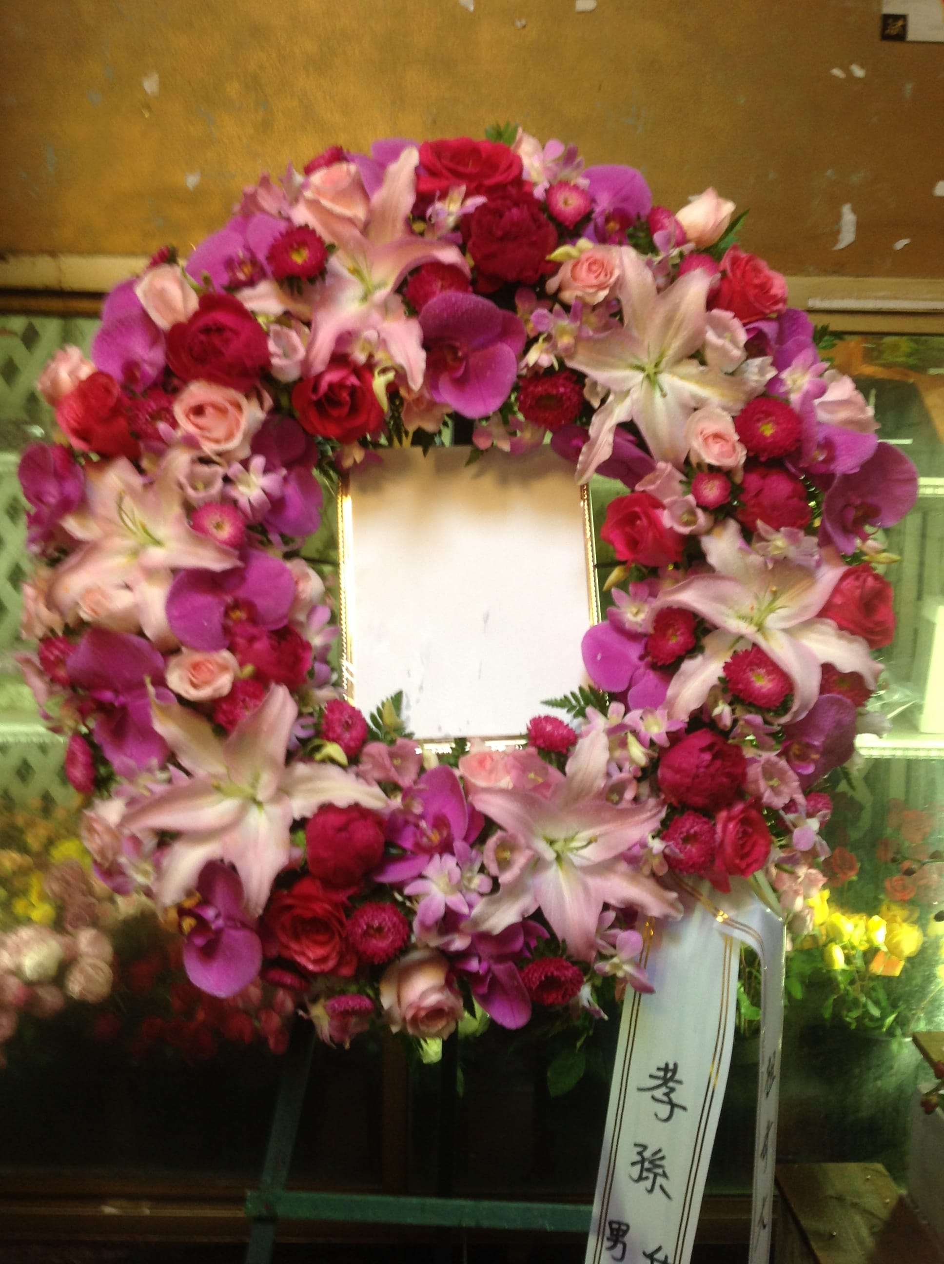 Heart-shaped floral wreath with pink and red flowers around a blank center