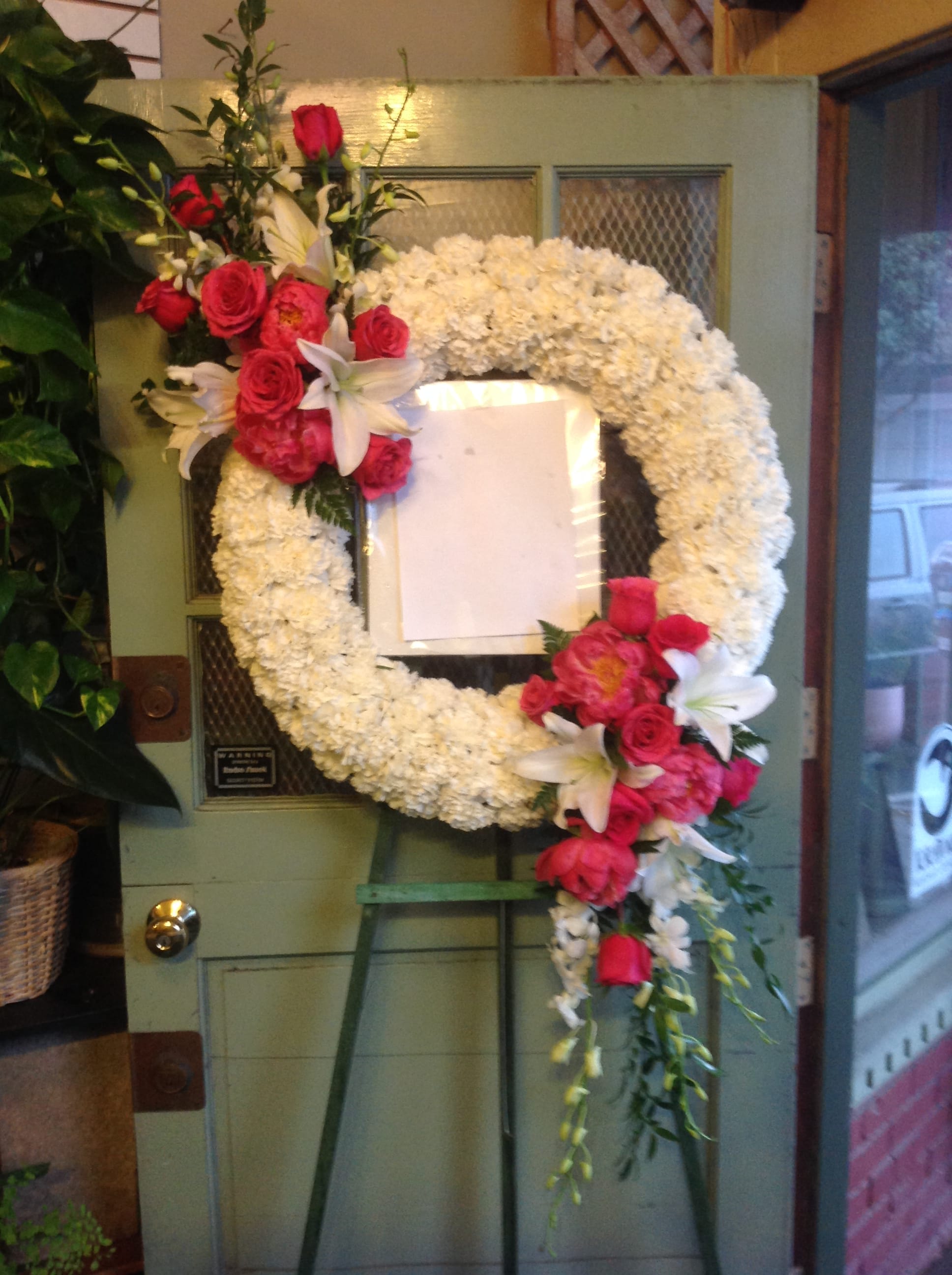 White floral wreath with pink roses and lilies on an easel