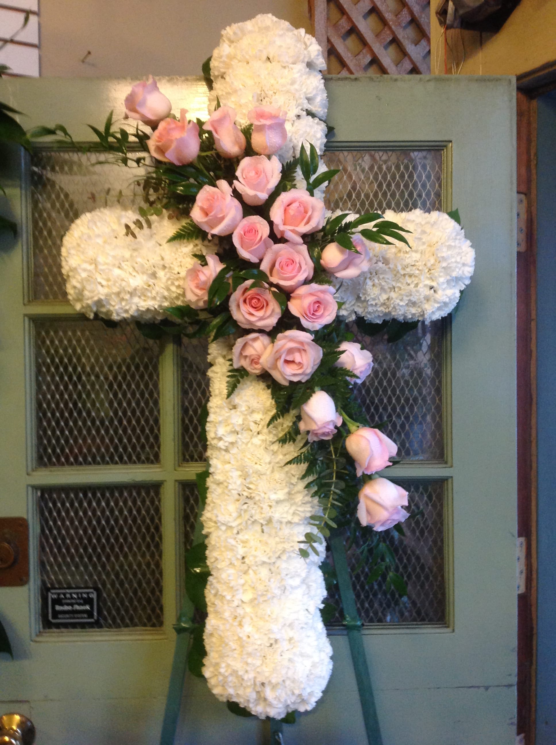 White floral cross with pink roses on a door