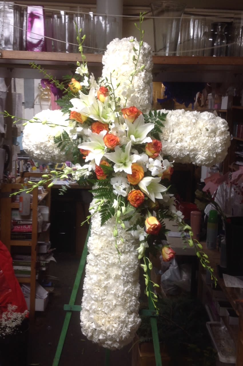 Large white floral cross with orange roses and lilies