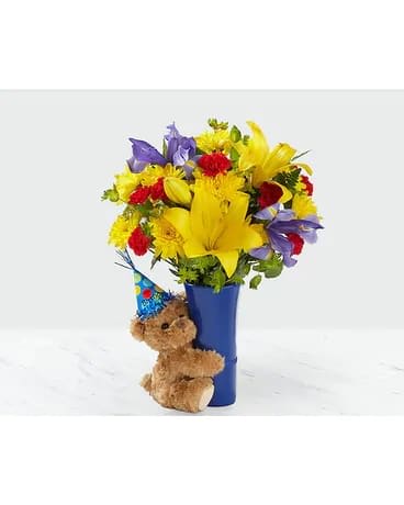 Bright mixed bouquet in a blue vase with a teddy bear attached
