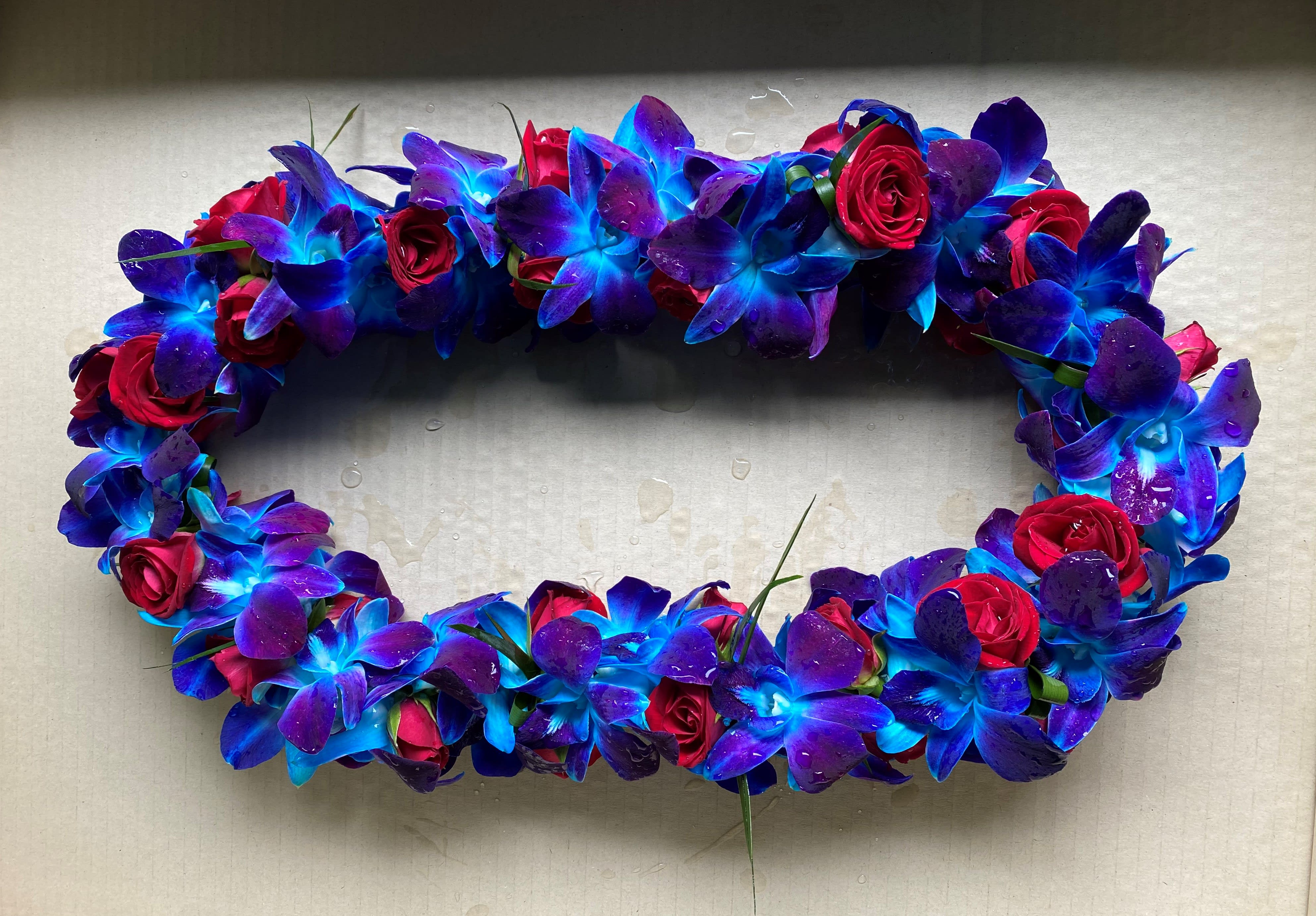 Oval floral wreath of blue-purple orchids and red roses