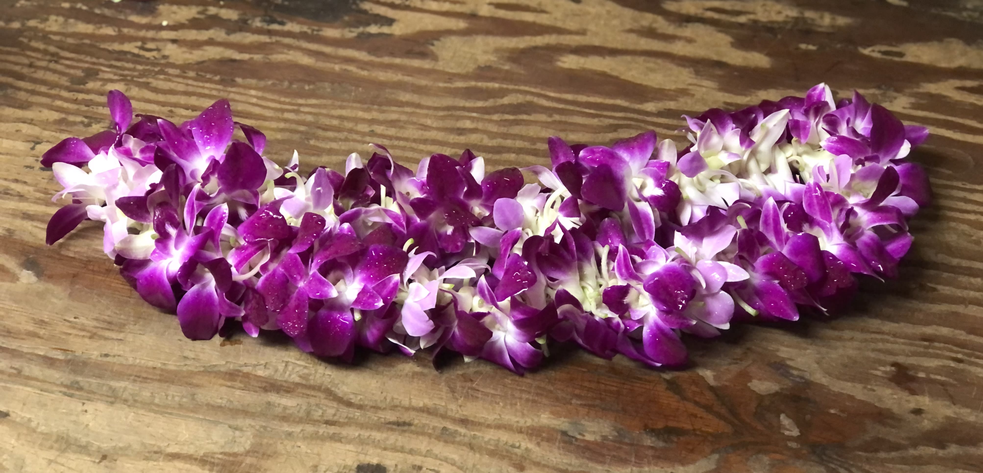 Purple orchid lei on a wooden surface