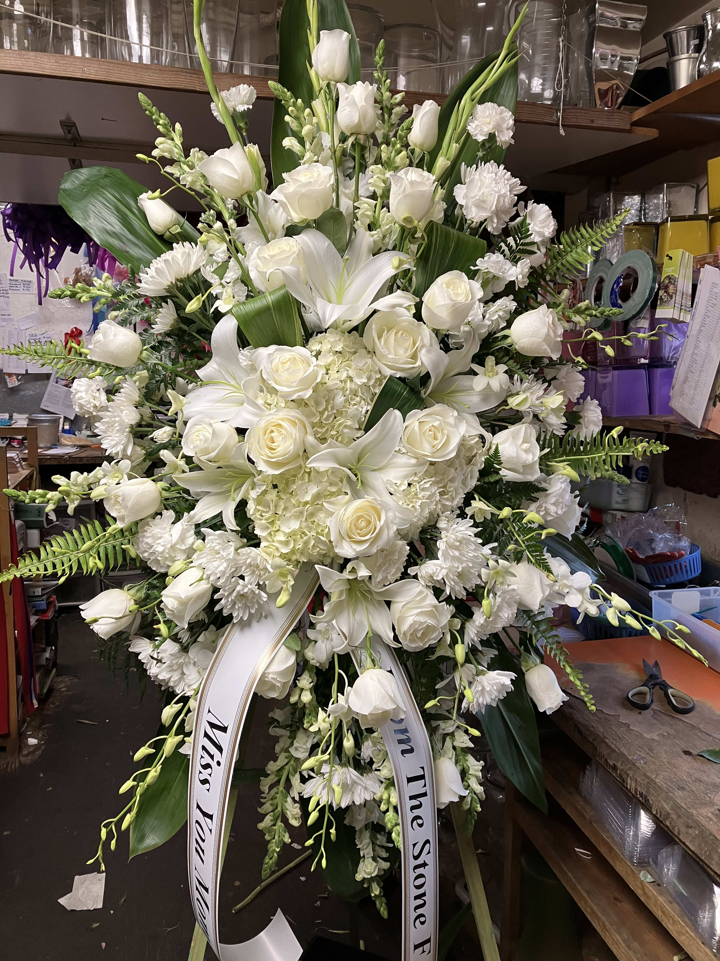 Large white funeral standing spray with roses and lilies